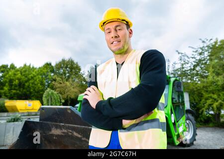 Builder ou conducteur debout devant des machines de construction sur chantier Banque D'Images