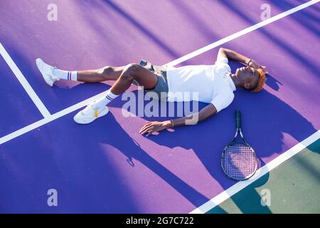 Jeune homme qui pose sur un court de tennis violet Banque D'Images