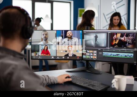 Chef de projet lors d'une réunion en ligne sur le Web avec l'équipe sur le travail du client d'édition d'appel vidéo, obtenir des commentaires sur le film commercial en utilisant le logiciel de post-production sur l'ordinateur dans le bureau d'agence de création de démarrage Banque D'Images