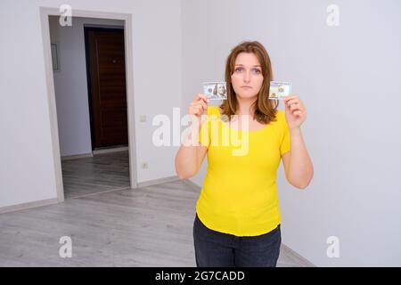 Une maison vide et de l'argent déchiré entre les mains d'une jeune femme. Crise des prêts HYPOTHÉCAIRES en dollars AMÉRICAINS Banque D'Images