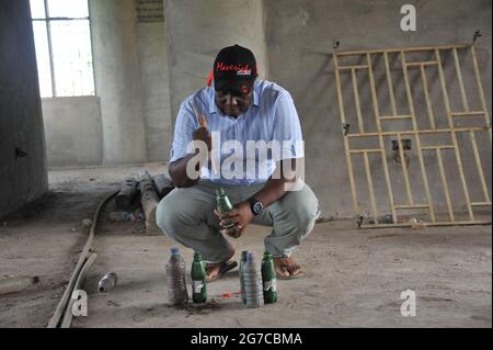 Accra, Ghana. 24 juin 2021. Martial Zohoungbogbo remplit le sol en bouteilles de plastique recyclées à l'intérieur de la bibliothèque communautaire qu'il a construite à Accra, au Ghana, le 24 juin 2021. Martial Zohoungbogbo, un architecte qui détient une double citoyenneté du Ghana et du Bénin, a construit une bibliothèque communautaire avec 45,000 bouteilles en plastique recyclées à la périphérie d'Accra. POUR ALLER AVEC "Feature: L'architecte africain construit une bibliothèque communautaire avec 45,000 bouteilles en plastique recyclé" crédit: Seth/Xinhua/Alamy Live News Banque D'Images