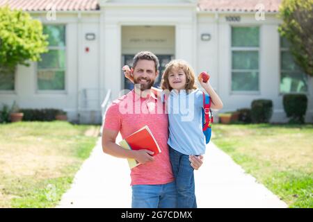 Père marchant fils à l'école. Parent et élève de l'école primaire avec sac à dos. Banque D'Images