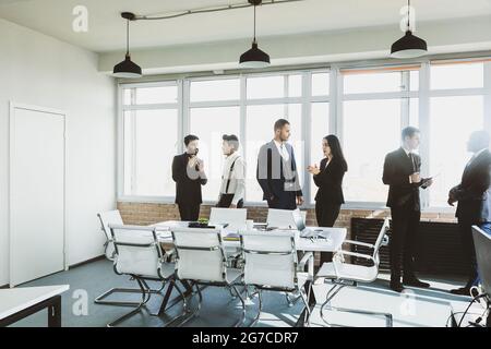 Silhouettes de personnes contre la fenêtre. Une équipe de jeunes hommes d'affaires travaillant et communiquant ensemble dans un bureau. Affaires professionnelles et Banque D'Images