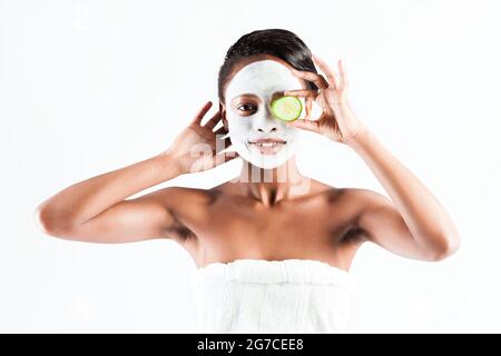 Jeune femme africaine en Studio faisant corps avec le concombre masque facial rafraîchissant pour les jeunes et une belle peau et de détente Banque D'Images