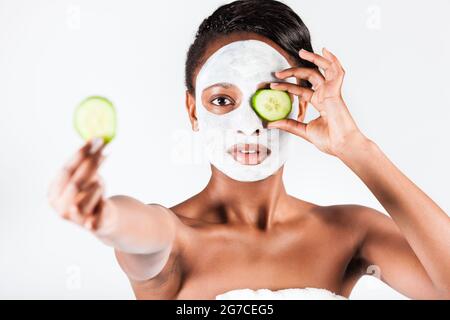 Jeune femme africaine en Studio faisant corps avec le concombre masque facial rafraîchissant pour les jeunes et une belle peau et de détente Banque D'Images