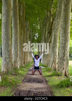 Jolie jeune femme africaine avec des tresses noires faisant des sauts dans le parc Banque D'Images