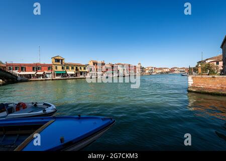 L'île de Murano, au cours d'une journée ensoleillée de printemps, célèbre pour la production de verre artistique. Canal avec bateaux amarrés et maisons. Lagune de Venise, Vénétie, Italie, UE. Banque D'Images