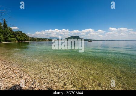 Belle plage sur le lac de Garde (Lago di Garda) en face de la petite ville de Garda. Pointe de San Vigilio (Punta San Vigilio), Vérone, Vénétie, Italie. Banque D'Images