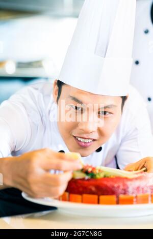 Portrait of Asian chef decorating cake Banque D'Images