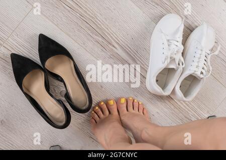 Une femme choisit entre des baskets confortables et des chaussures de bureau. Vue de dessus Banque D'Images