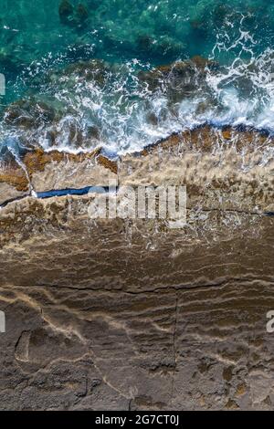 Vagues de mer se brisant sur la côte rocheuse, vue verticale aérienne directement au-dessus Banque D'Images