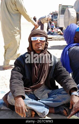 WAW al Kabir, Libye - 29 mars 2006 : un chauffeur de Tuareg portant des lunettes de protection alors que les gens se préparent à regarder l'éclipse solaire totale au Sahara Banque D'Images