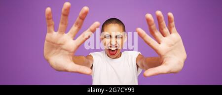 Portrait grand angle d'une femme heureuse sur fond violet. Modèle féminin avec tête rasée et mains à l'avant. Banque D'Images