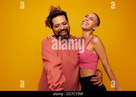 Portrait d'une femme avec son ami gay masculin sur fond jaune. Des amis de Happt souriant ensemble en studio. Banque D'Images