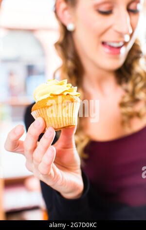 Femme présentant des muffins et cupcakes en boulangerie ou pâtisserie Banque D'Images