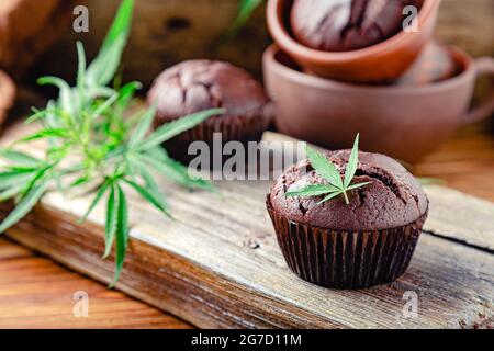 Muffins au chocolat avec des feuilles de cannabis, de l'herbe cbd. Médicaments marijuana chanvre drogues dans le dessert alimentaire. Cuisson des muffins aux mauvaises herbes au chocolat. Cupcake Banque D'Images