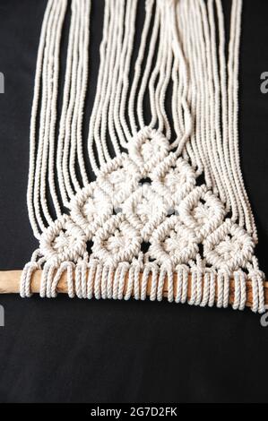 Gros plan sur le motif de texture macrame fait main. Décoration murale en coton macrame 100 faite à la main avec manche en bois. Décoration moderne à l'intérieur. Banque D'Images