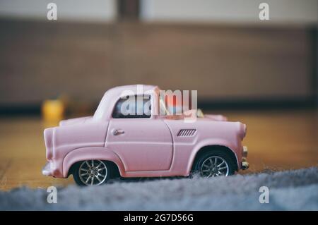 POZNAN, POLOGNE - 13 novembre 2016 : une voiture miniature rose sur le plancher en bois Banque D'Images