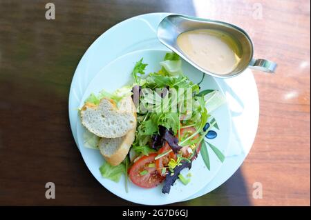 Salade fraîche de laitue et de tomates avec pain et vinaigrette française sur une assiette blanche comme en-cas d'été sain, vue d'en haut, sélectionné Banque D'Images