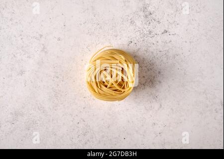 Fettuccine brute non cuite sur fond texturé gris. Copier l'espace. Vue de dessus Banque D'Images