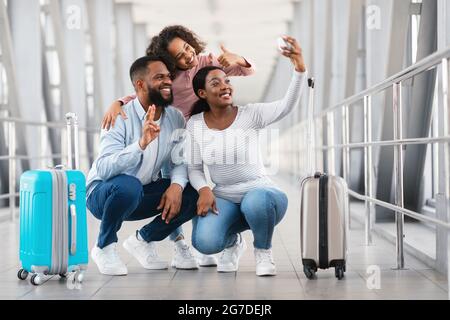 Famille noire de trois personnes voyageant, emportant le selfie à l'aéroport Banque D'Images