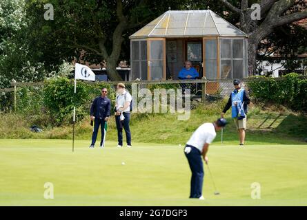 Un résident regarde Justin Rose en Angleterre sur le 4ème green pendant la journée d'entraînement au Royal St George's Golf Club à Sandwich, dans le Kent. Date de la photo: Mardi 13 juillet 2021. Banque D'Images