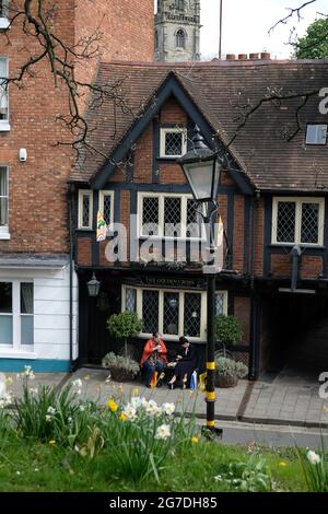 Deux femmes sont assises à l'extérieur de Princess Street, Shrewsbury, dans le Shopshire. Ils boivent du café et des en-cas. Jonquilles en premier plan St Alkmund en arrière-plan Banque D'Images