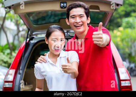 Asian couple loading valise pour voyager dans les bagages coffre de voiture Banque D'Images