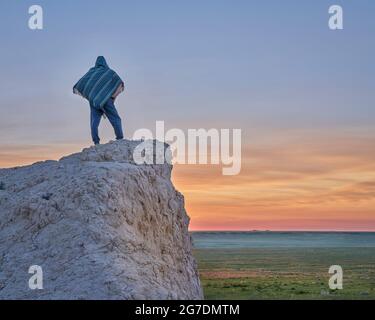 Homme dans un poncho mexicain regardant le lever du soleil au-dessus de la prairie - paysage d'été dans le Grassland national de Pawnee, dans le nord du Colorado Banque D'Images