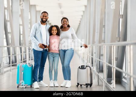 Bonne famille noire excitée voyageant, posant à l'aéroport Banque D'Images