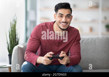 Jeune homme arabe jouant à des jeux vidéo à la maison Banque D'Images