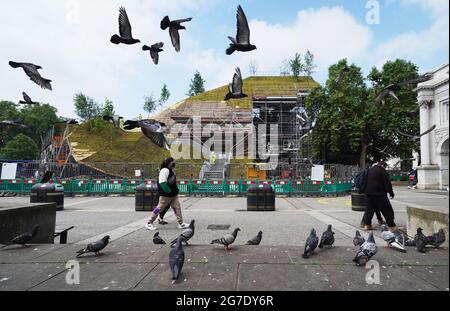 Les travaux se poursuivent sur le Marble Arch Mound dans le centre de Londres. Le sommet de la nouvelle installation de 25 mètres de haut offrira des vues panoramiques sur Hyde Park, Mayfair et Marylebone lors de son ouverture au public en juillet. La colline artificielle a été construite sur une base d'échafaudage, avec des couches de sol et de contreplaqué formant le monticule qui a un centre creux avec de l'espace pour les expositions et les expositions. Date de la photo: Mardi 13 juillet 2021. Banque D'Images