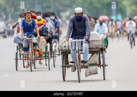 Les tireurs de pousse-pousse transportent des passagers sur la route de l'aéroport, dans la matinée à Dhaka, le lundi 11 juillet. Les pousse-pousse sont normalement interdits d'utilisation des routes, mais sont autorisés pendant le verrouillage actuel. Le Bangladesh traverse une vague de COVID-19, avec un record de 13768 cas le lundi 12 juillet. Le 14 juillet, les restrictions au confinement seront assouplies pendant neuf jours pour les célébrations d'Eid-ul-Azha. Les tireurs de pousse-pousse comptent parmi les travailleurs les moins bien payés au Bangladesh et ont ressenti les restrictions très durement. Au cours des efforts précédents sur le verrouillage, les tireurs de pousse-pousse où Banque D'Images