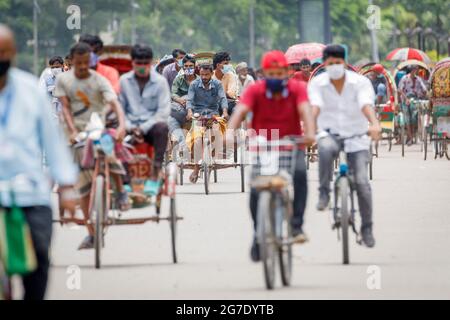 Les tireurs de pousse-pousse transportent des passagers sur la route de l'aéroport, dans la matinée à Dhaka, le lundi 11 juillet. Les pousse-pousse sont normalement interdits d'utilisation des routes, mais sont autorisés pendant le verrouillage actuel. Le Bangladesh traverse une vague de COVID-19, avec un record de 13768 cas le lundi 12 juillet. Le 14 juillet, les restrictions au confinement seront assouplies pendant neuf jours pour les célébrations d'Eid-ul-Azha. Les tireurs de pousse-pousse comptent parmi les travailleurs les moins bien payés au Bangladesh et ont ressenti les restrictions très durement. Au cours des efforts précédents sur le verrouillage, les tireurs de pousse-pousse où Banque D'Images