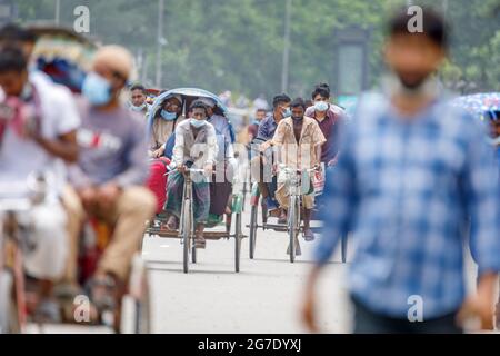 Les tireurs de pousse-pousse transportent des passagers sur la route de l'aéroport, dans la matinée à Dhaka, le lundi 11 juillet. Les pousse-pousse sont normalement interdits d'utilisation des routes, mais sont autorisés pendant le verrouillage actuel. Le Bangladesh traverse une vague de COVID-19, avec un record de 13768 cas le lundi 12 juillet. Le 14 juillet, les restrictions au confinement seront assouplies pendant neuf jours pour les célébrations d'Eid-ul-Azha. Les tireurs de pousse-pousse comptent parmi les travailleurs les moins bien payés au Bangladesh et ont ressenti les restrictions très durement. Au cours des efforts précédents sur le verrouillage, les tireurs de pousse-pousse où Banque D'Images