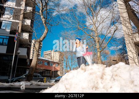 Femme marchant dans la neige à la fin de l'hiver à parler au téléphone Banque D'Images