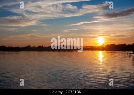 Coucher de soleil coloré sur un lac calme. Le soleil se reflète sur la surface de l'eau. Banque D'Images
