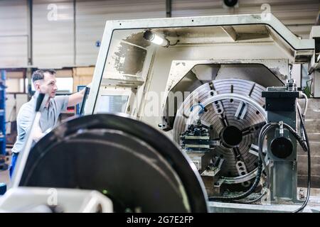 Ouvrier utilisant un tour CNC en usine Banque D'Images