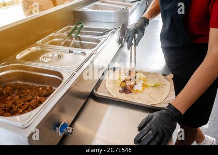 Femme préparant burrito dans un camion alimentaire Mettre les ingrédients dans le pain Tortilla Banque D'Images