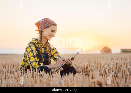 Agriculteur femme calculant le rendement de récolte après une longue journée d'utilisation stylo et papier Banque D'Images