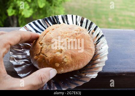 Repas femelle Mung dal kachori snack. Personne tenant la main kachouri. Extérieur nature fond sur la table balcon. En-cas de petit-déjeuner indien Banque D'Images