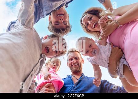 prise de vue depuis le dessous d'un jeune adulte en famille, pour s'amuser à l'extérieur. portrait de maman et de papa transportant des enfants en vacances avec des enfants. vue basse et courte Banque D'Images