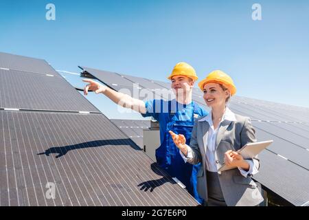 Travailleur et investisseur dans une centrale solaire pointant vers le soleil Banque D'Images