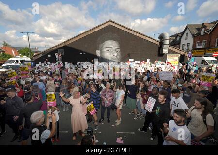 Les gens se rassemblent devant une manifestation prévue pour soutenir l'attaquant de Manchester United et le joueur d'Angleterre Marcus Rashford devant sa murale sur le mur du café Coffee House sur Copson Street, Withington. La fresque paraissait vandalisée lundi après que l'équipe de football d'Angleterre ait perdu la finale de l'UEFA Euro 2021. Date de la photo: Mardi 13 juillet 2021. Banque D'Images