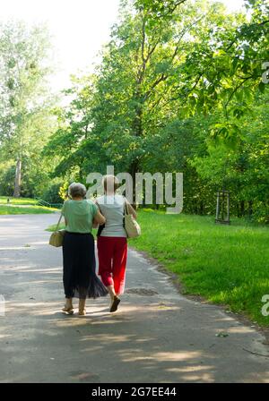 POZNAN, POLOGNE - 22 mai 2014 : un sentier le long de l'herbe verte et des arbres et deux femmes marchant dans un parc de la région de Piastowskie Banque D'Images