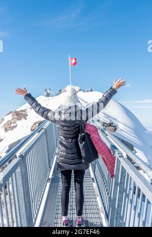 Femme non reconnue portant des vêtements d'hiver levant les bras et appréciant la journée dans la neige. Banque D'Images