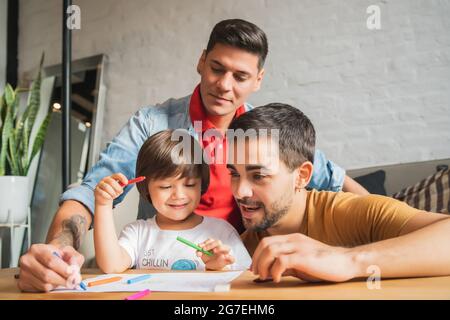 Couple gay et leur fils s'amusant ensemble tout en dessinant à la maison. Banque D'Images