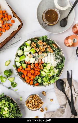 Salade de kale aux saveurs automnales de patate douce rôtie, de choux de bruxelles, de pommes et de noix Banque D'Images