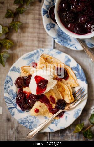 Une assiette de crêpes nappée de sauce à la cerise et de glace à la vanille Banque D'Images