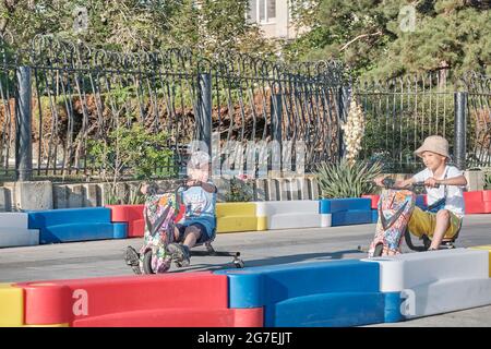 Sudak, Ukraine - 12 juin 2021 : deux petits garçons qui sont à bord d'un scooter électrique de kart dans un parc d'attractions par une journée ensoleillée d'été. Ils concurrencent wi Banque D'Images